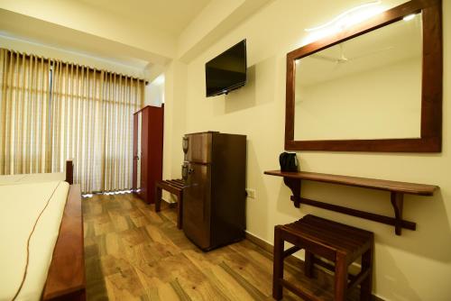 a room with a bed and a desk and a mirror at Chaaya inn Hotel in Hikkaduwa