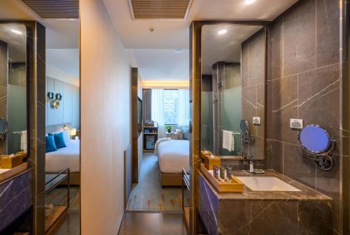 a bathroom with a sink and a room with a bed at Novotel Melbourne Central in Melbourne