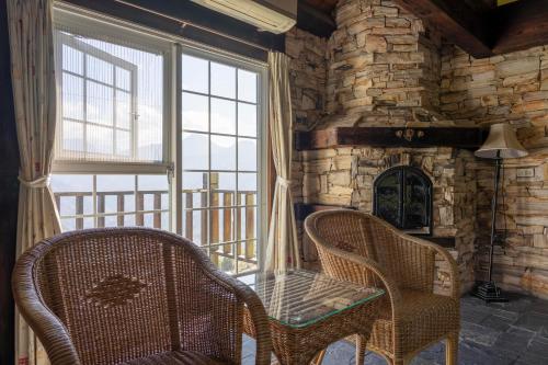 a room with two chairs and a stone fireplace at Provence Rose Lodge in Renai