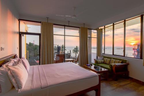 een slaapkamer met een bed en uitzicht op de oceaan bij Chaaya inn Hotel in Hikkaduwa