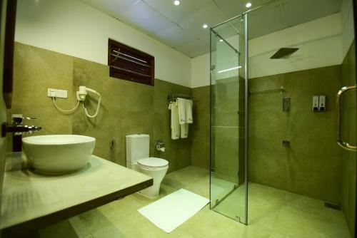a bathroom with a toilet and a glass shower at Chaaya inn Hotel in Hikkaduwa