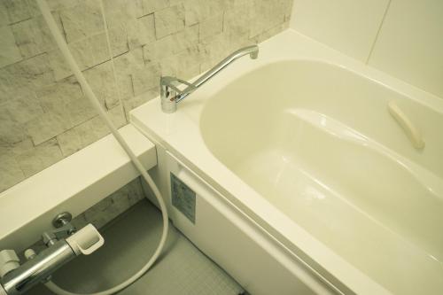 a bathroom with a white tub and a toilet at OBI HOUSE B1母屋room in Shimo-tatsuda
