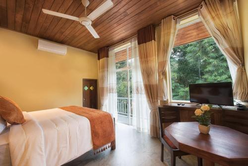 a bedroom with a bed and a desk and a window at Sobaya Hotel in Kandy