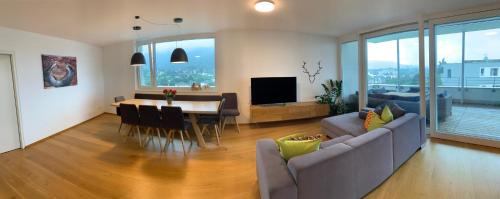 a living room with a couch and a table at Luxus Penthouse Bregenz Feldmoos mit Whirlpool & riesen Terrasse, nahe Festspiele in Bregenz