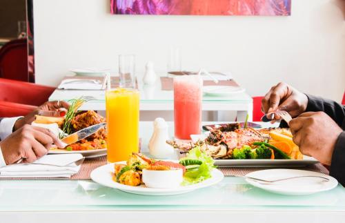 a group of people sitting at a table eating food at Onomo Hotel Dar es Salaam in Dar es Salaam
