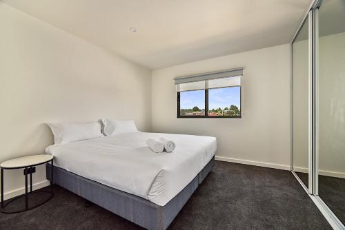 a white bedroom with a bed and a window at Southern Apartments Launceston in Launceston