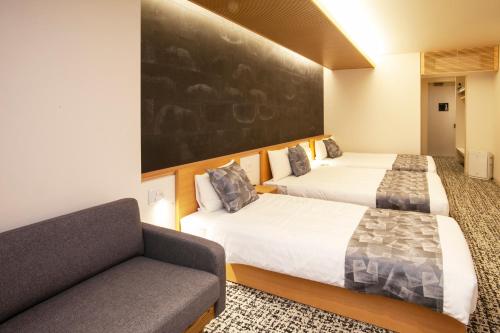 a hotel room with two beds and a couch at GRAND BASE Osu in Nagoya