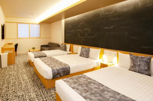 a room with three beds and a chalkboard on the wall at GRAND BASE Osu in Nagoya