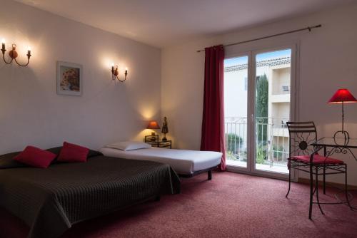 a bedroom with two beds and a balcony at The Originals City, Hôtel Le Village Provençal, Aix-en-Provence Nord (Inter-Hotel) in Pertuis