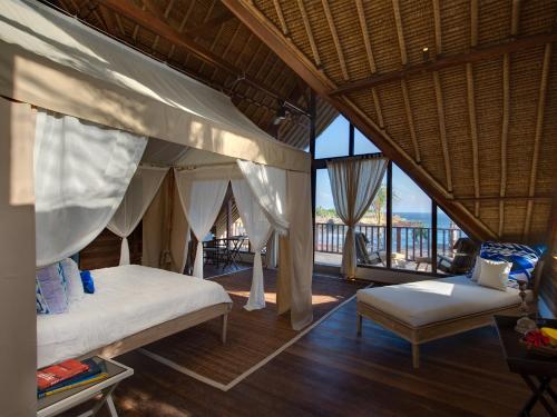 Un dormitorio con una cama y una silla en una habitación. en Villa Voyage, en Nusa Lembongan