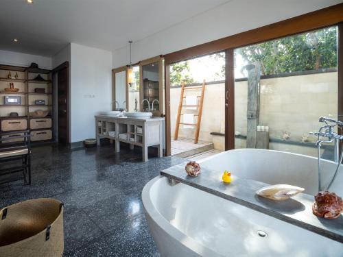 baño grande con bañera y lavamanos en Villa Voyage, en Nusa Lembongan