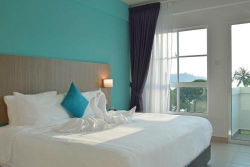 AVI Pangkor Beach Resort في بانكور: سرير أبيض كبير في غرفة مع نافذة