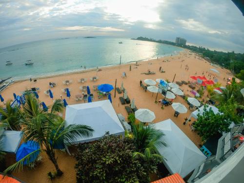 a beach with umbrellas and people on the sand at Peacock Beach Hotel Unawatuna in Unawatuna