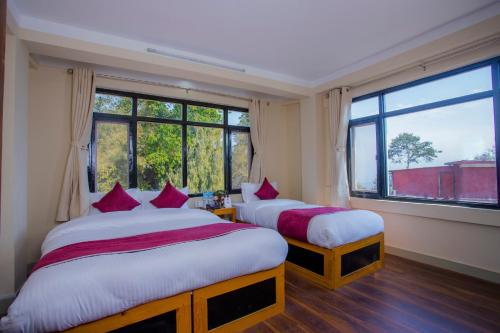 2 camas en una habitación con 2 ventanas en Asha Lodges, en Dhulikhel