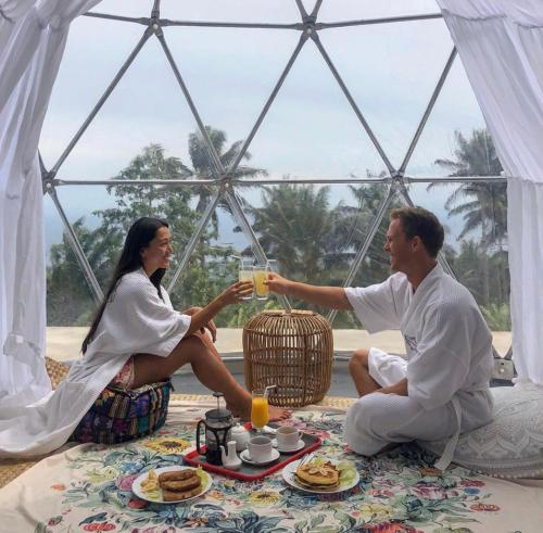 a man and woman sitting in a tent drinking orange juice at Bintana sa Paraiso Binunsaran in Mambajao