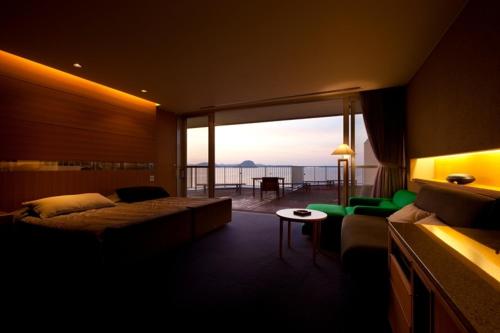 een slaapkamer met een bed en uitzicht op de oceaan bij Hotel Uohan in Karatsu