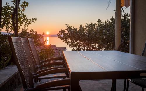 a table and chairs with the sunset in the background at MORE Podgora Luxury Design Apartment in Podgora