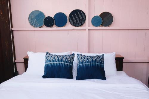 a bed with blue pillows and plates on a wall at บ้านเสงี่ยม-มณี Baan Sa ngiam-Manee in Sakon Nakhon