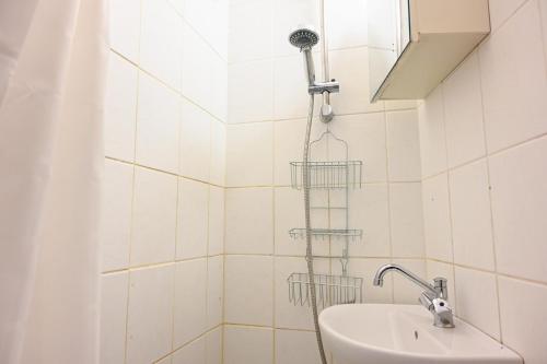 a shower in a white tiled bathroom with a sink at Sanders Park - Charming 1-Bdr Apt Close to Metro in Copenhagen