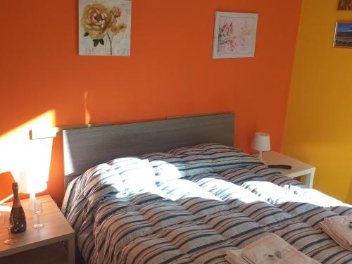a bed in a room with an orange wall at Bed Relax Etnaview in Zafferana Etnea