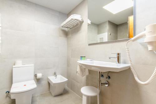 a bathroom with a sink and a toilet and a mirror at Hotel Castilla Alicante in Alicante