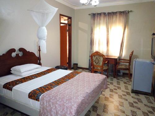 a bedroom with a bed and a table and chairs at Peniel Beach Hotel in Entebbe
