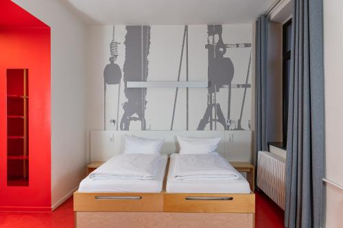 a bedroom with a bed and a red wall at havenhostel Bremerhaven in Bremerhaven