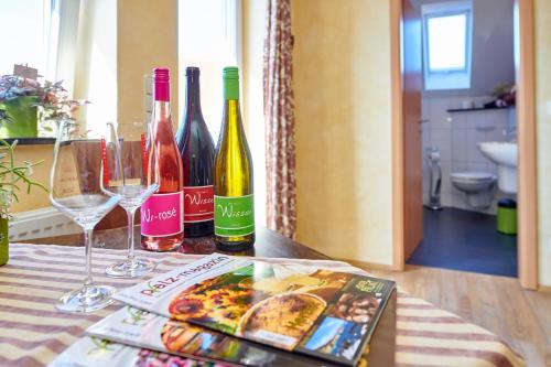 una mesa con botellas de vino y copas y una revista en Weingasthaus Wisser, en Billigheim-Ingenheim