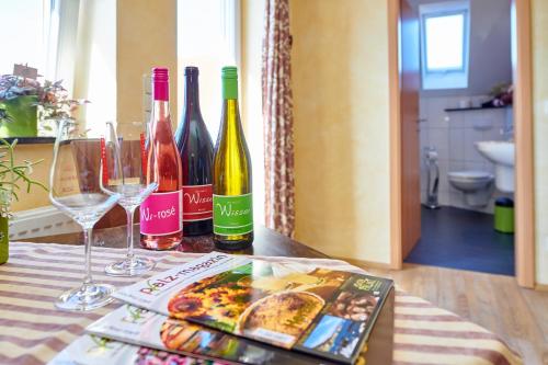 a table with wine bottles and glasses and a magazine at Weingasthaus Wisser in Billigheim-Ingenheim