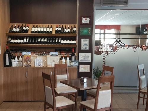 un restaurante con mesa, sillas y botellas de vino en Albergue Piñeiral Fonsagrada, en Fonsagrada