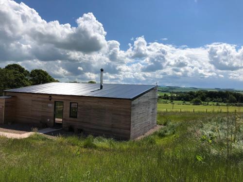 a small wooden building in a field with a sky at Tweed Hideaway in Kelso