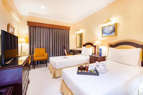 a hotel room with two beds and a television at Blue Sky Pandurata Hotel Cikini in Jakarta