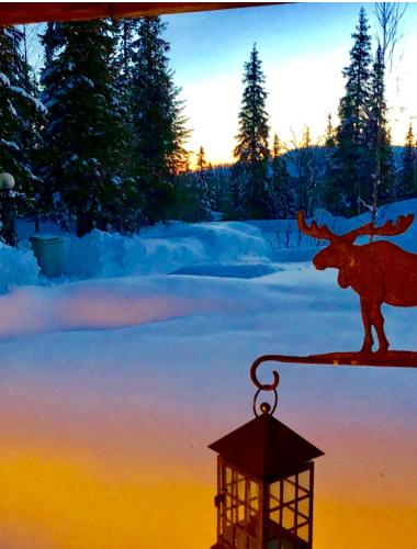 a lantern with a moose on it next to a snow covered field at Villa Karhunkehto in Luosto