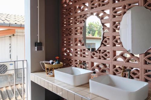 a bathroom with two sinks and a mirror at บ้านเสงี่ยม-มณี Baan Sa ngiam-Manee in Sakon Nakhon