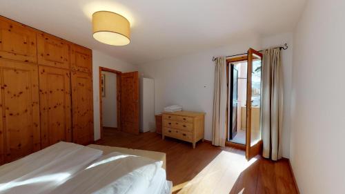 1 dormitorio con 1 cama, vestidor y ventana en La Dmura en Samedan