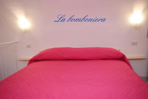 a bedroom with a pink bed with a sign on the wall at La Bomboniera in Maiori