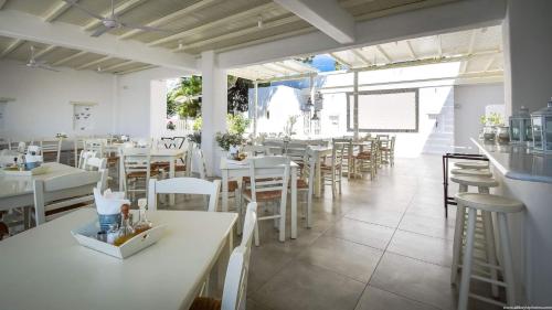 a restaurant with white tables and white chairs at Hotel Ivi in Drios