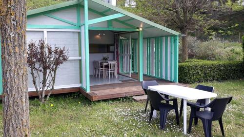 a green and white shed with a table and chairs at Domaine Camping les Roches in Le Crestet