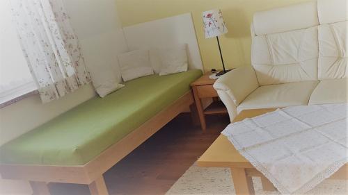 a living room with a green couch and a chair at Ferienwohnung Szöky in Bad Mitterndorf