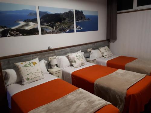 a room with three beds and three pictures on the wall at Pension Vilanova in Sigüeiro