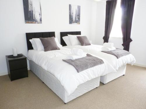 1 dormitorio con 2 camas con sábanas blancas y almohadas grises en 8 Cathedral Street en Dunkeld