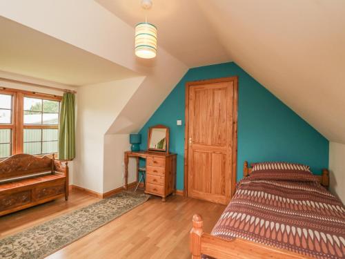 a bedroom with blue walls and a bed and a window at Kamba Cottage in Tannadice