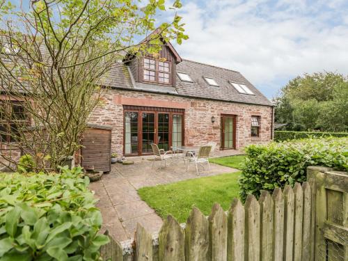 a brick house with a wooden fence in the yard at Nantusi Cottage in Tannadice
