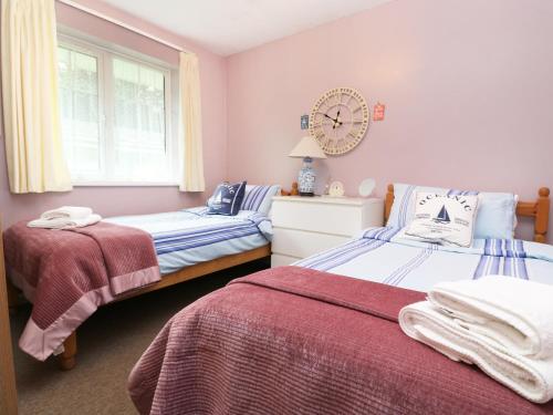 1 dormitorio con 2 camas y reloj en la pared en No 1 The Heathers, en Saint Cleer