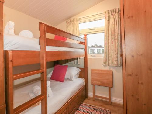 a bunk bed room with two bunk beds and a chair at Tiggy Winkle in St Merryn