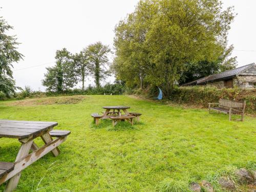 a picnic table and benches in a field at Treverbyn Smithy in Saint Neot