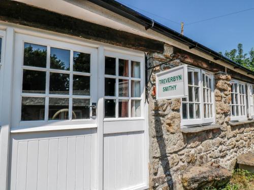 a white garage door and a sign on a stone building at Treverbyn Smithy in Saint Neot