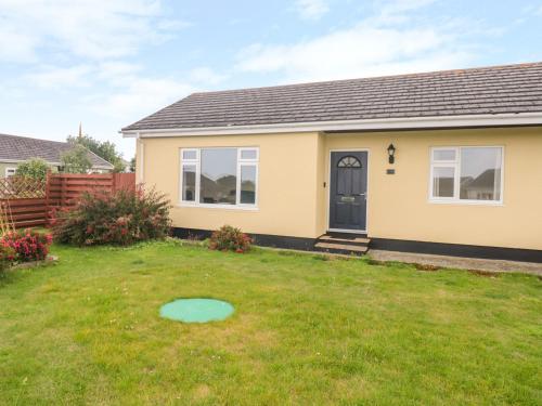 a yellow house with a blue door in a yard at Merlin's Retreat in Tintagel