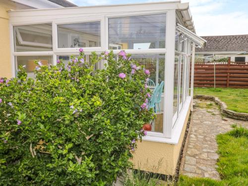 a house with a conservatory with pink flowers at Merlin's Retreat in Tintagel