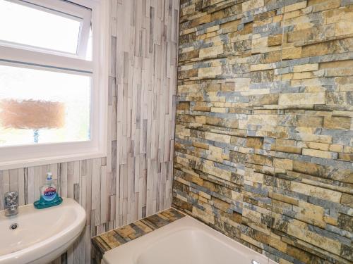 a bathroom with a white sink and a brick wall at Merlin's Retreat in Tintagel